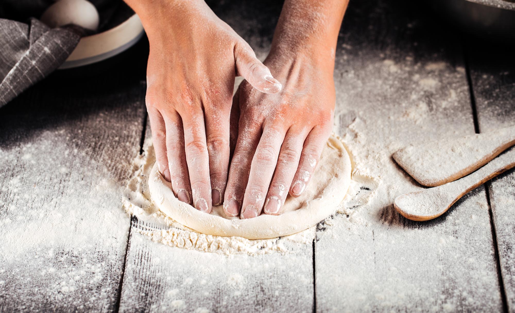 Hands kneading dough on floured board